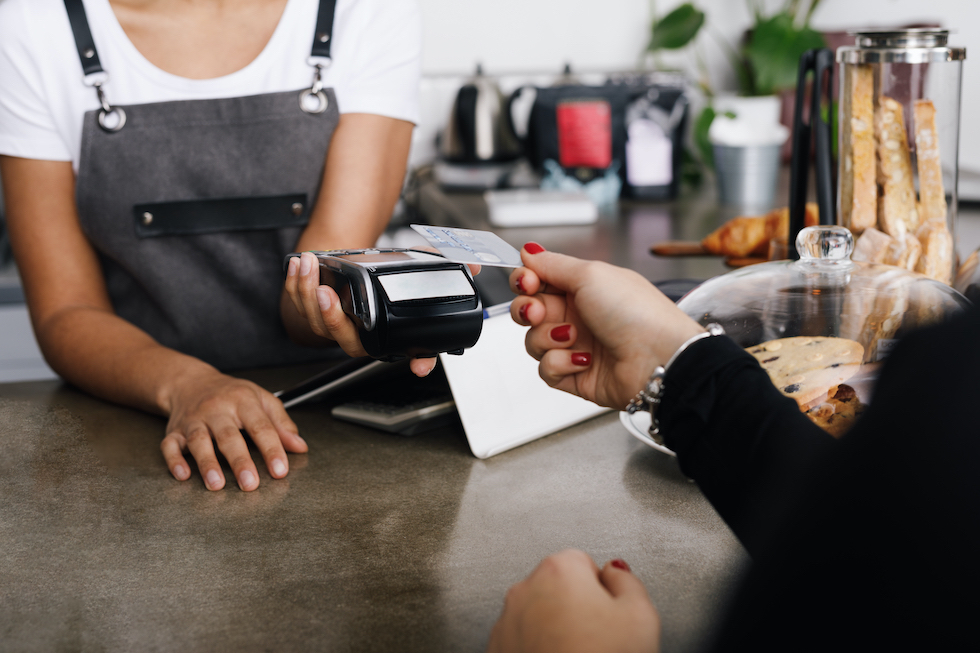 A woman using a card reader to process a credit card payment in-store.