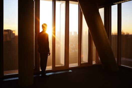 Businessman looks out at city sunrise and contemplates selling his products cross border.