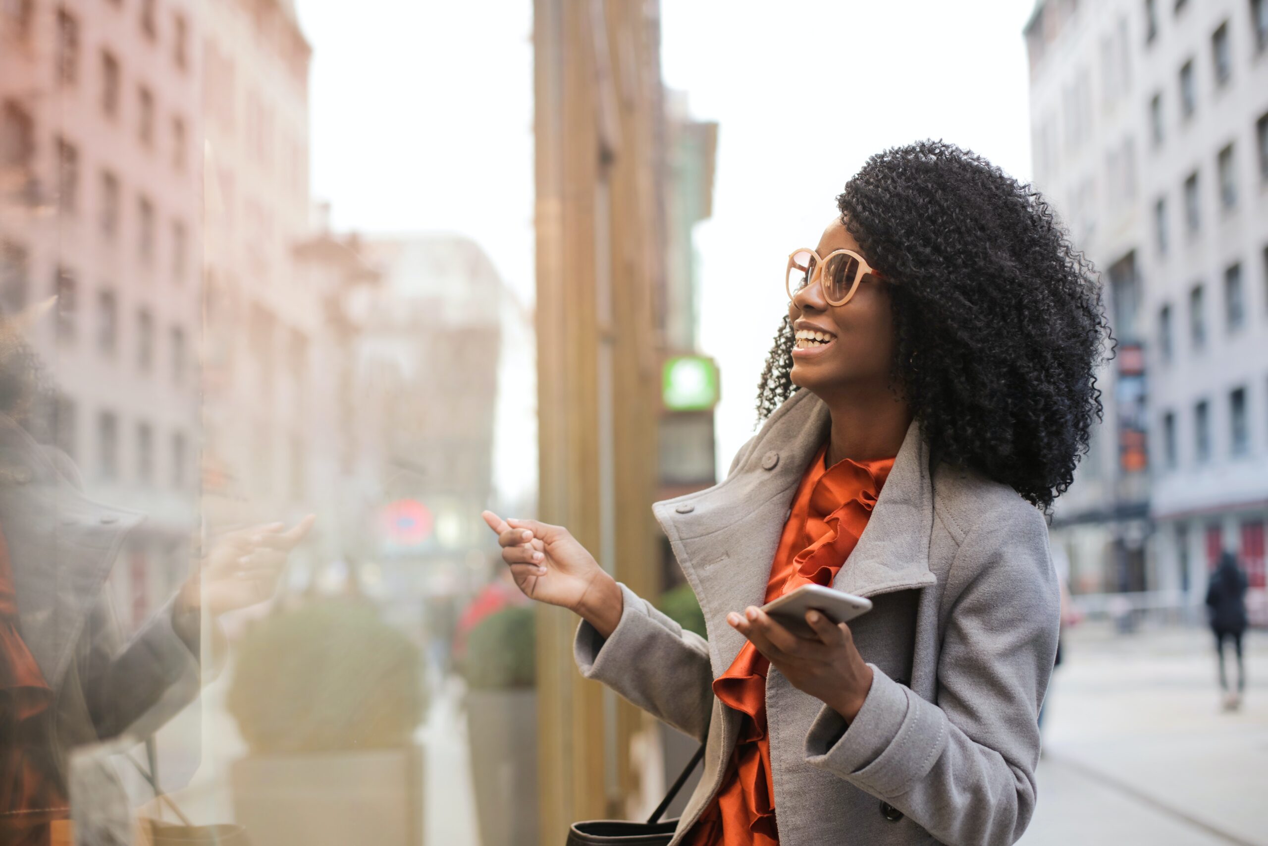 Woman in glasses holds phone in city