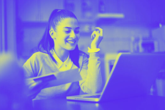 A woman works on the computer and smiles, representing the digital checkout: how to accept credit card payments online